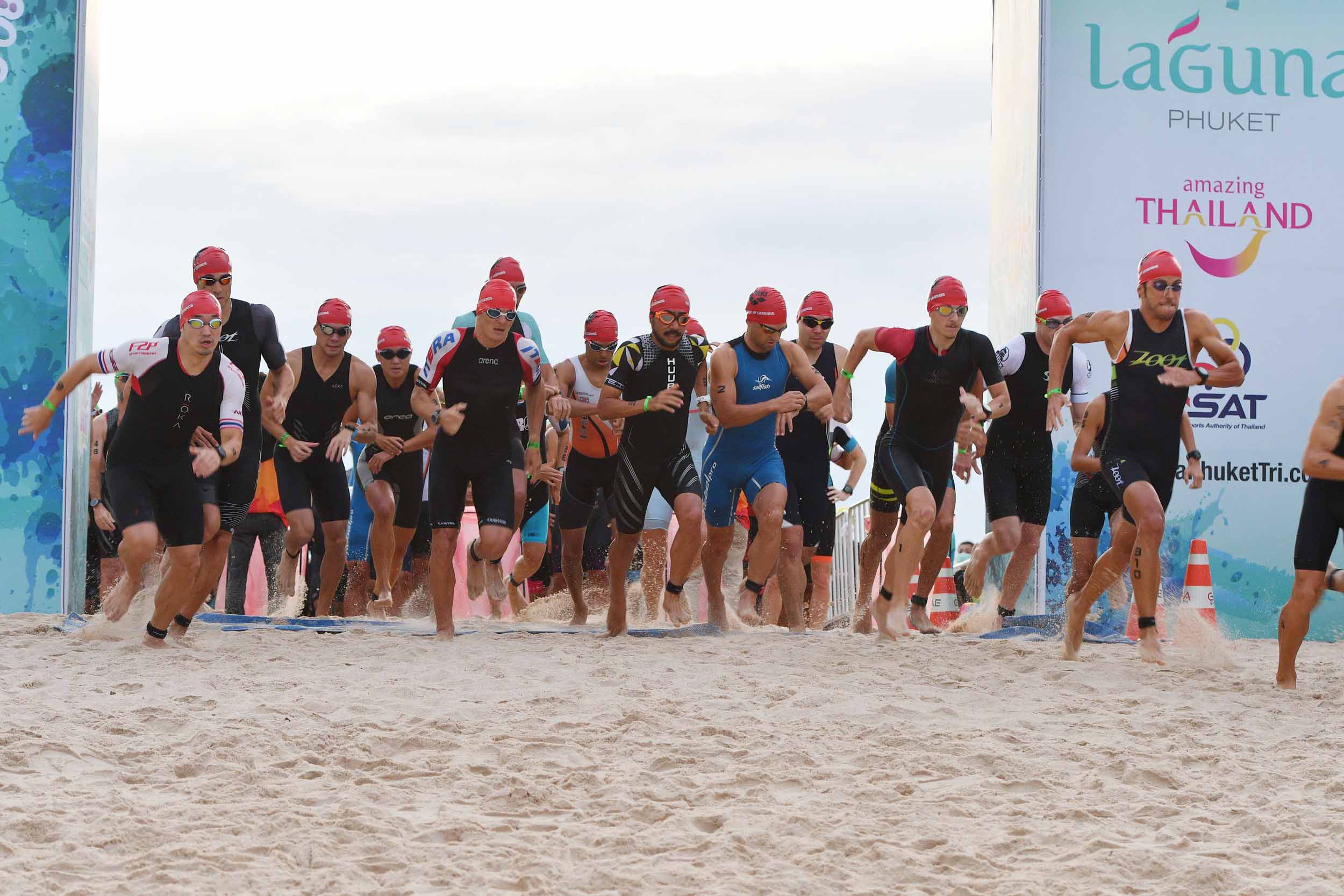 Triathletes running from the beach at the start of Laguna Phuket Triathlon