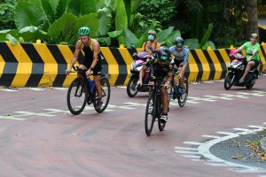 Triathletes cycling past tropical greenery during race